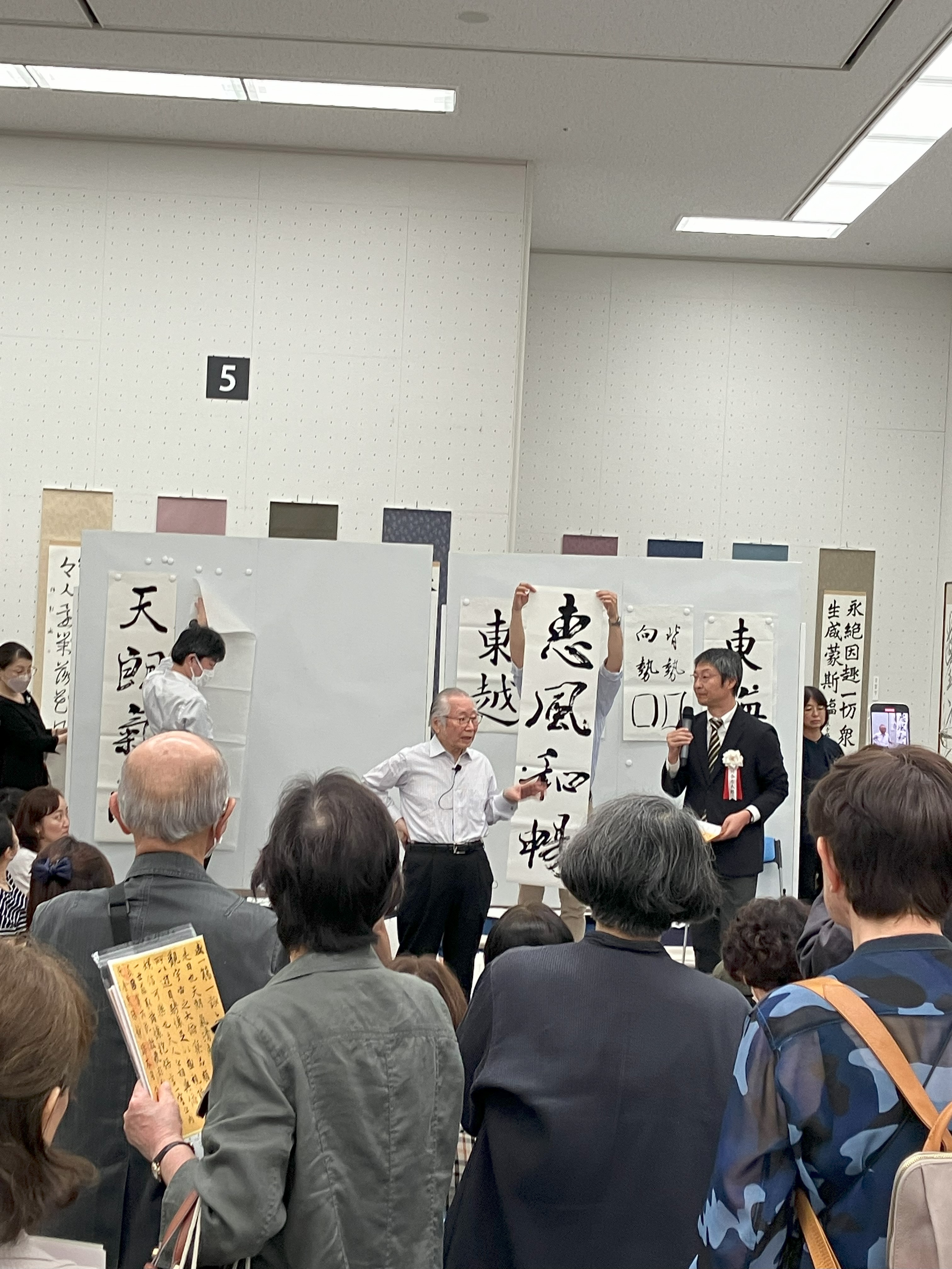 ライブで書き上げられた書を前に解説する石飛先生(中央)/展示会場にて